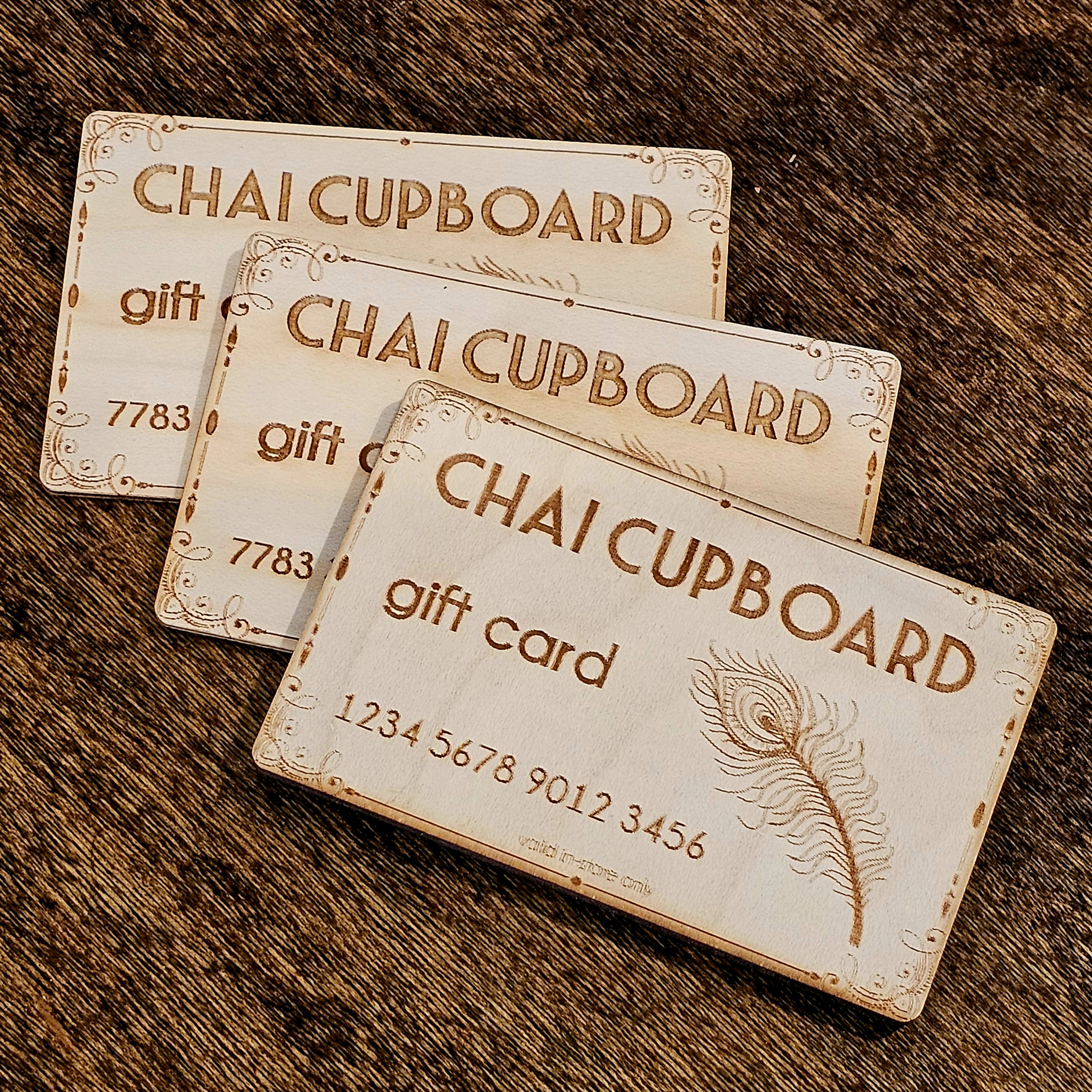 photograph of three laser-cut and engraved wooden gift cards for Chai Cupboard